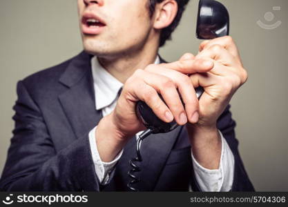 Businessman is covering the phone to speak in private to someone in the room