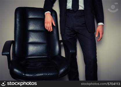 Businessman is standing by a large director&rsquo;s chair
