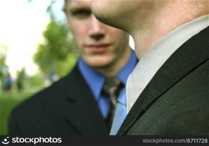 Businessman is stealthily looking at you from behind another businessman