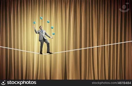 Businessman juggling with balls. Young businessman balancing on rope and juggling with balls