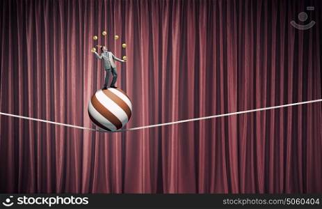 Businessman juggling with balls. Young businessman standing on ball juggling with balls