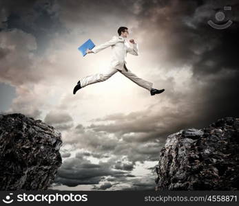 Businessman jumping over gap. Image of young businessman jumping over gap