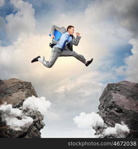 Businessman jumping over gap. Image of young businessman jumping over gap