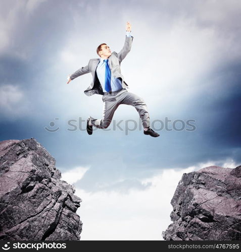 Businessman jumping over gap. Image of young businessman jumping over gap