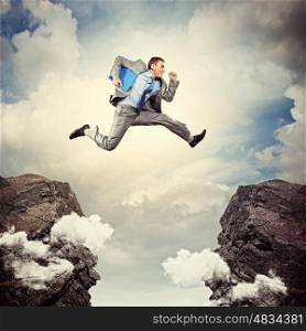 Businessman jumping over gap. Image of young businessman jumping over gap