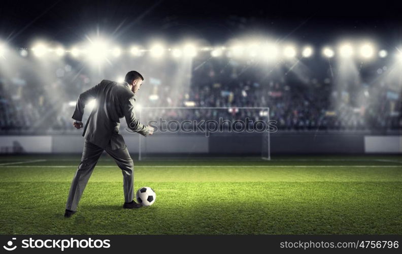 Businessman kicking ball. Young businessman in suit playing football at stadium