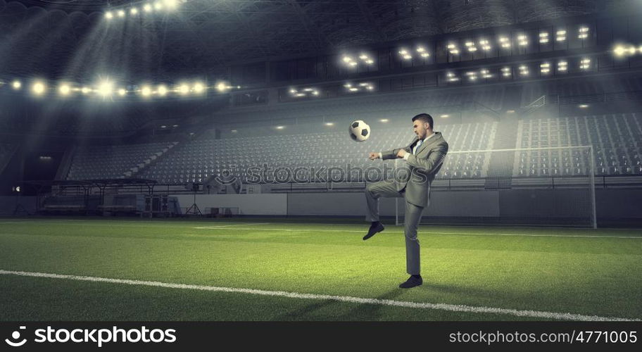 Businessman kicking ball. Young businessman in suit playing football at stadium