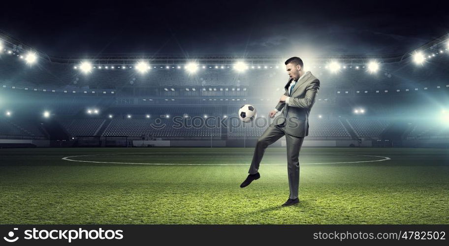 Businessman kicking ball. Young businessman in suit playing football at stadium