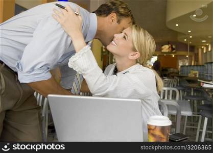 Businessman kissing a businesswoman in a restaurant