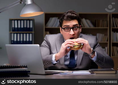 Businessman late at night eating a burger