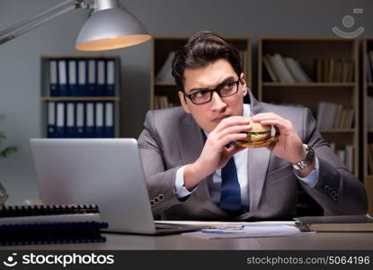 Businessman late at night eating a burger