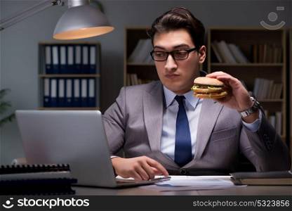Businessman late at night eating a burger