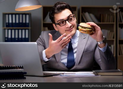 Businessman late at night eating a burger