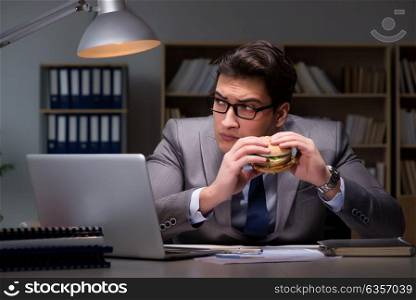 Businessman late at night eating a burger