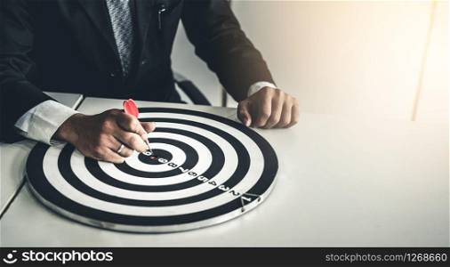 Businessman leader aiming at mission target. Concept of challenge in business marketing bullseye and intelligent customer reach. The dart is the strategy or skill. The dartboard is the project goal.