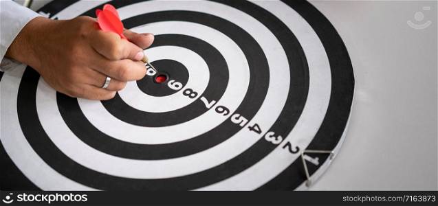 Businessman leader aiming at mission target. Concept of challenge in business marketing bullseye and intelligent customer reach. The dart is the strategy or skill. The dartboard is the project goal.