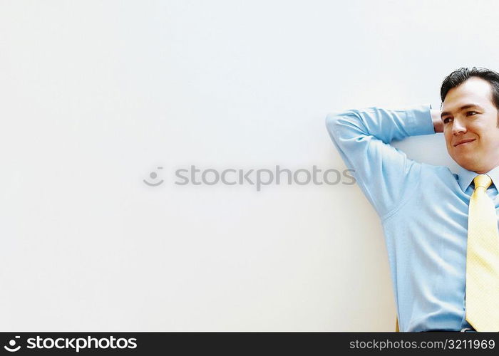 Businessman leaning against a wall and smiling