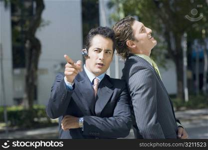 Businessman leaning against another businessman and pointing forward