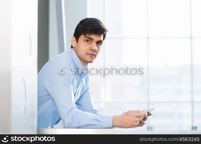 Businessman leaning on balcony railings. Successful and confident businessman with tablet in modern building interior