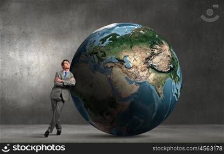 Businessman leaning on huge Earth planet. Elements of this image are furnished by NASA. World is mine