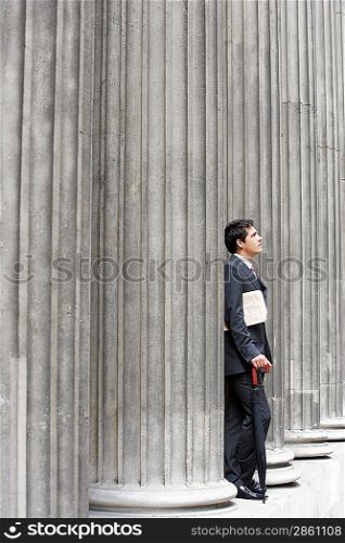 Businessman Leaning on Pillar
