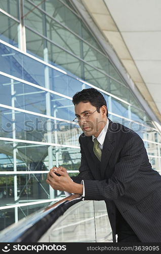 Businessman leaning on railing outside office building