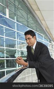 Businessman leaning on railing outside office building