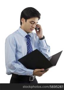 Businessman looking at a file while talking on a mobile phone
