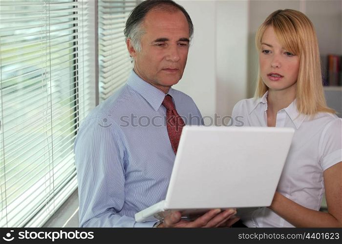 Businessman looking at a laptop with his assistant
