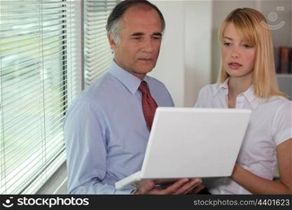 Businessman looking at a laptop with his assistant
