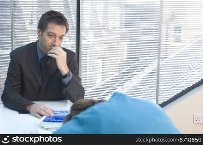 Businessman looking at a mid adult woman sleeping at a desk