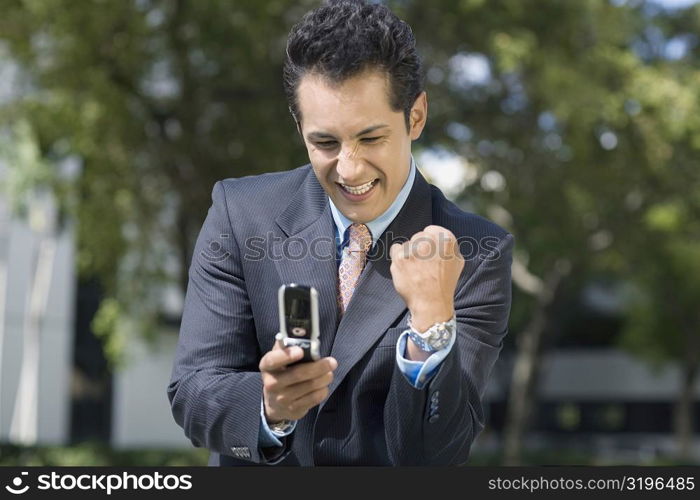 Businessman looking at a mobile phone and making a fist