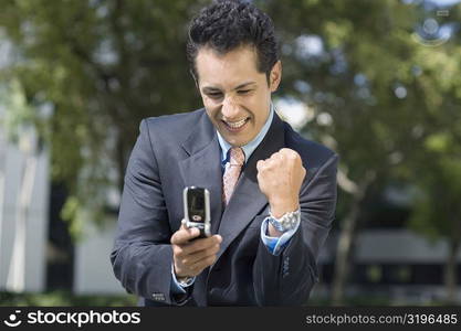 Businessman looking at a mobile phone and making a fist