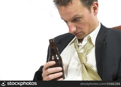 Businessman looking at his bottle of beer crosseyed