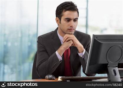 Businessman looking at monitor screen in office