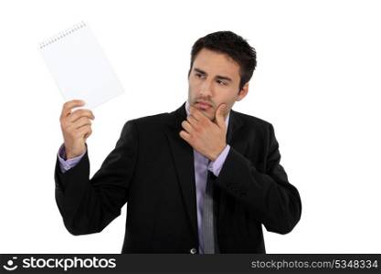 Businessman looking at notepad curiously