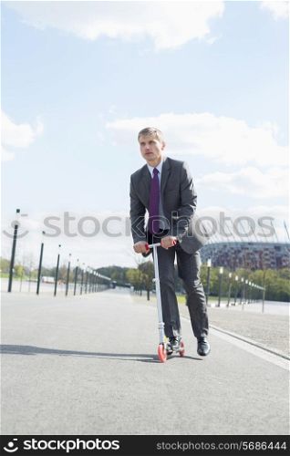 Businessman looking away while riding scooter on street