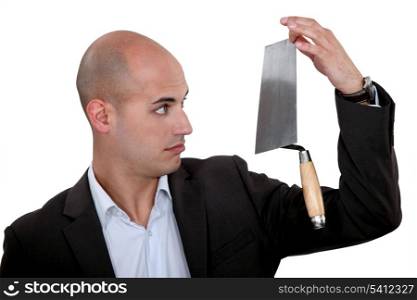 Businessman looking disbelievingly at a trowel