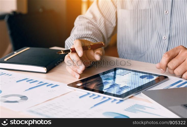 Businessman looking graph and summary report on digital tablet screen with analysis data result.