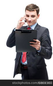 Businessman looking in a folder and talking on the phone on a white background