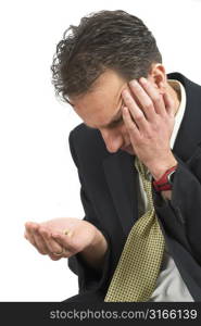 Businessman looking indecisive at the pills in his hand