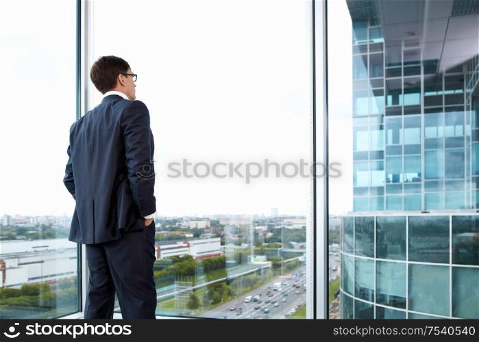 Businessman looking out of his office on the opposite building