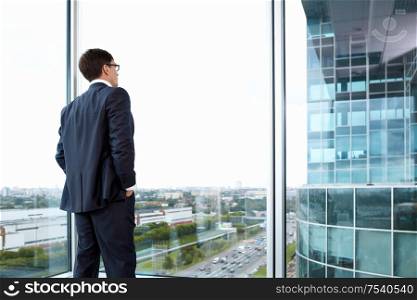Businessman looking out of his office on the opposite building