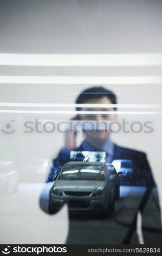 Businessman looking thorough window in parking garage, reflection of car