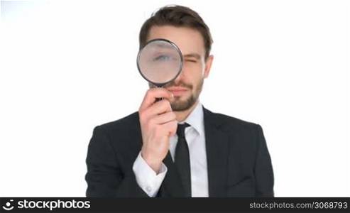 Businessman looking through a magnifying glass enlarging one eye, conceptual of research, investigation, analysis and information, isolated on white