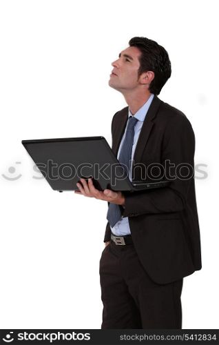 Businessman looking upwards and holding a laptop