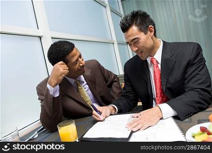 Businessman looking while another businessman signs agreement