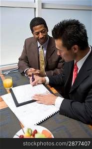 Businessman looking while another businessman signs agreement