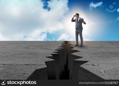 Businessman looking with binoculars at cliff edge