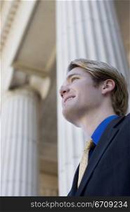 Businessman looks ahead and smiles as he stands in front of columns